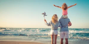 A family standing on the beach, looking out towards the waves.